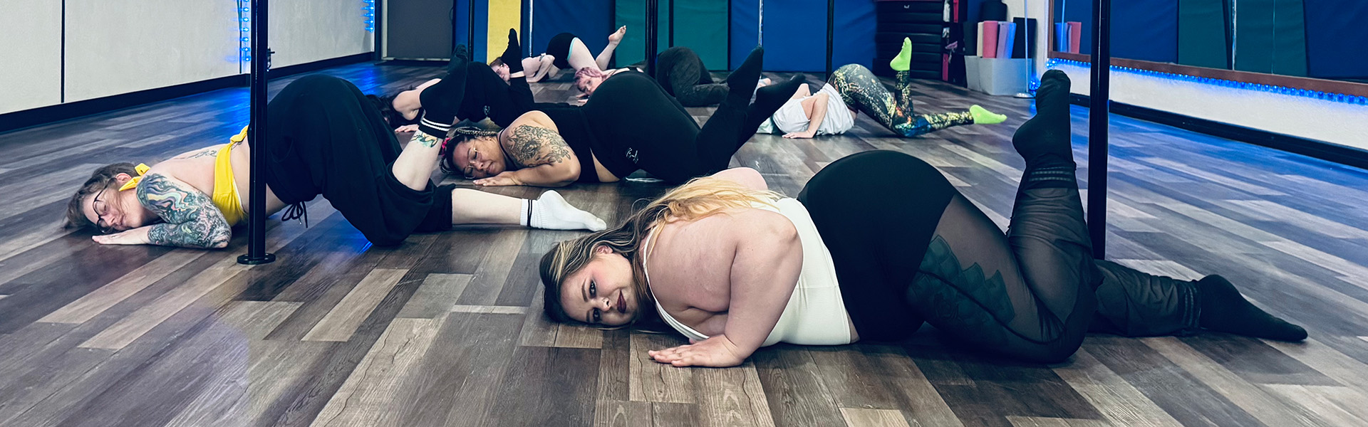 A group of people doing floorwork in a pole studio